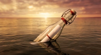 Flasche mit Papier schwimmt im Meer bei Sonnenuntergang.