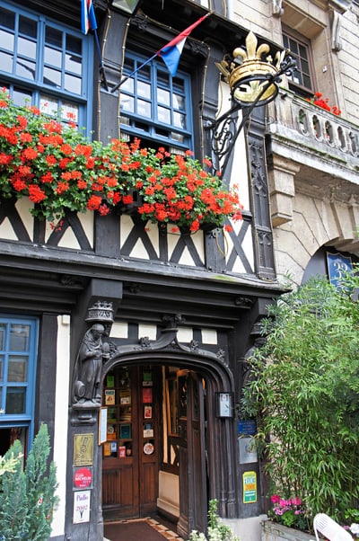 Historische Fachwerkfassade mit Blumen und dekorativem Schild.