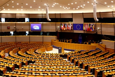 Innenansicht eines grossen, leeren Konferenzsaals mit runden Sitzreihen und vielen Flaggen.