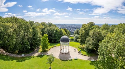 Blick auf Kuppelbau in grüner Parklandschaft.