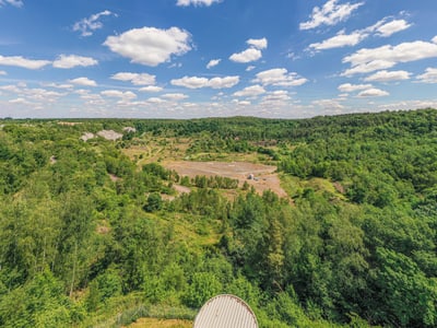 Landschaftsansicht mit bewaldeten Hügeln unter blauem Himmel.