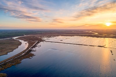 Luftaufnahme von Landschaft mit Fluss und Sonnenuntergang.
