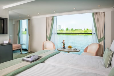 Innenraum einer Schiffskabine mit Blick auf Wasser und Ufer.