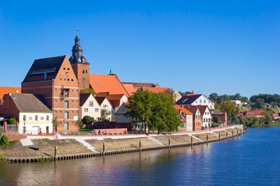 Historische Gebäude am Flussufer mit blauem Himmel.