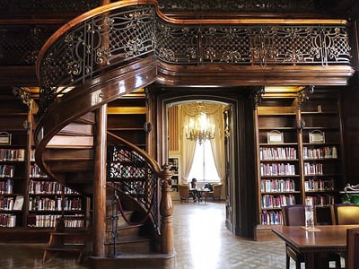 Holztreppe und Regale in einer eleganten Bibliothek.