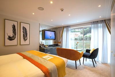 Modernes Hotelzimmer mit Bett, Fernseher und Sitzbereich am Fenster.