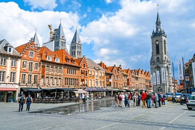 Marktplatz mit historischen Gebäuden, Turm und Menschen, die spazieren.