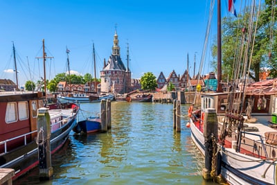 Hafen mit historischen Booten und Turm im Hintergrund.
