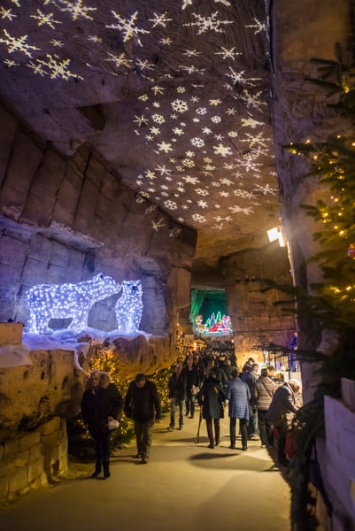 Weihnachtslichter und Menschen in einer beleuchteten Höhle.
