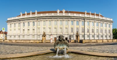 Blick auf ein grosses historisches Gebäude mit Brunnen im Vordergrund.
