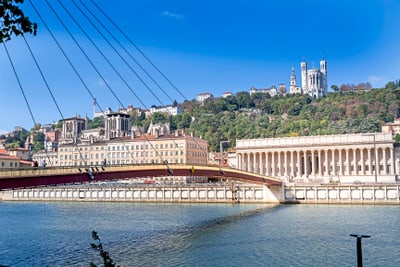 Fluss in Lyon mit Brücke und Hügel im Hintergrund.