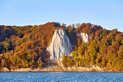 Kreidefelsen auf Rügen mit Herbstwald und Meer im Vordergrund.
