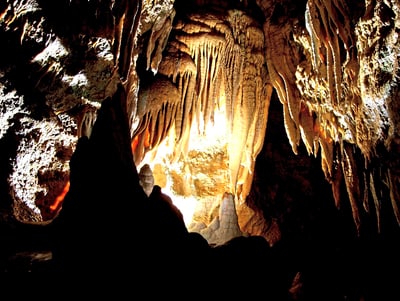 Beleuchtete Tropfsteinhöhle mit Stalaktiten und Stalagmiten.