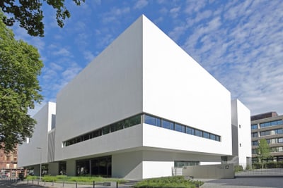 Modernes weisses Gebäude mit grossen Fenstern und blauem Himmel.