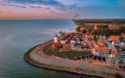 Luftaufnahme von Küstendorf mit Leuchtturm und Meer.