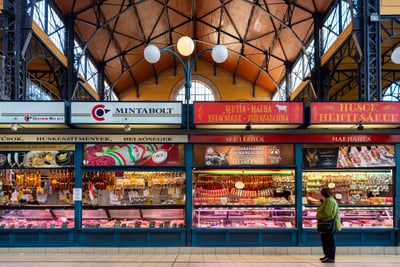 Fleischstand in einer Markthalle mit Kunden.