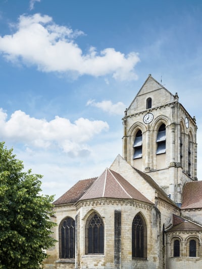 Historische Kirche mit Turm und Uhr, blauer Himmel.