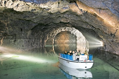 Bootsfahrt in einer beleuchteten Höhle mit Wasser.
