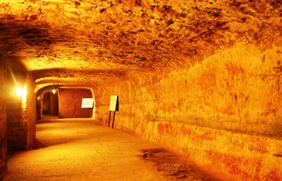 Beleuchteter Tunnel mit gewölbter Decke aus Stein.