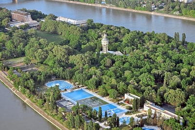 Luftaufnahme eines Parks mit Schwimmbädern und Fluss im Hintergrund.