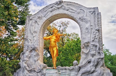 Goldene Statue eines Geigers in verzierter Steinarbeit.
