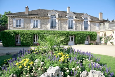 Historisches Steinhaus mit Garten voller Blumen.