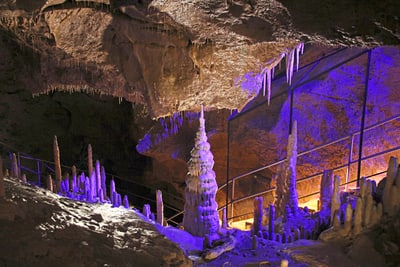 Stalagmiten und Stalaktiten in einer beleuchteten Höhle.