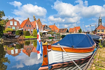 Hafen mit Booten und traditionellen Häusern bei blauem Himmel.