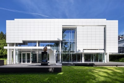Moderne weisse Fassade eines grossen Gebäudes mit Glasfront.