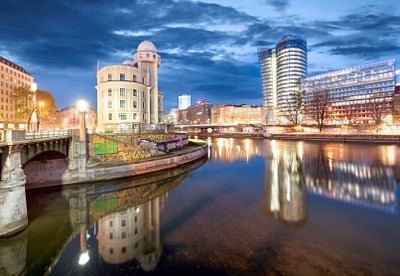 Stadtansicht bei Nacht mit Fluss und modernen Gebäuden.