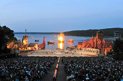 Freilichttheater am See mit brennendem Schiff.