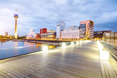 Holzsteg und beleuchtete Skyline am Abend in Düsseldorf.