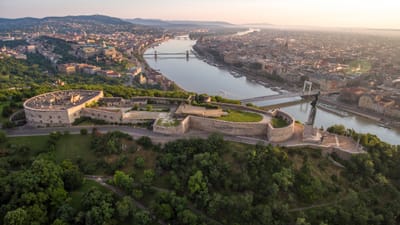 Luftaufnahme einer Festung neben einem Fluss mit einer Stadt im Hintergrund.