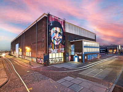 Straat Museum in Amsterdam mit bunter Fassadenkunst bei Sonnenuntergang.