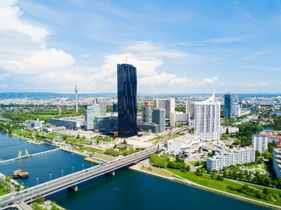 Luftaufnahme einer modernen Stadt mit hohen Gebäuden und einem Fluss im Vordergrund.