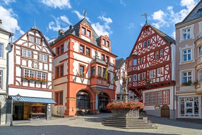 Historische Fachwerkhäuser mit Brunnen auf einem Platz.