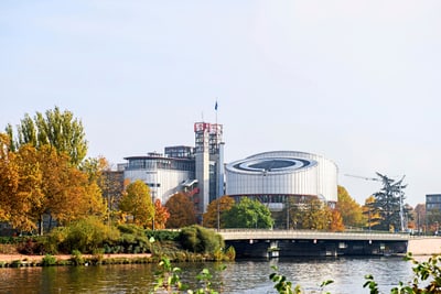 Moderne Gebäude am Flussufer mit herbstlichen Bäumen.