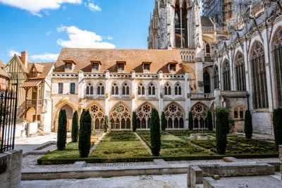 Garten vor alter Kathedrale mit Bäumen und gotischen Bögen.