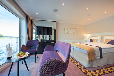 Elegantes Hotelzimmer mit Flussblick, zwei Sesseln und Tisch.
