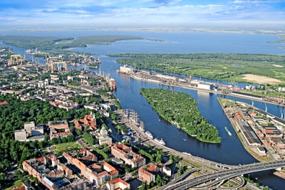 Luftaufnahme einer Stadt mit Fluss und Hafenanlagen.