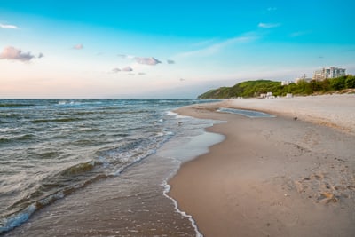 Sandstrand mit Wellen und blauem Himmel.