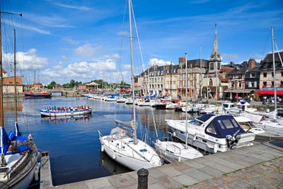 Hafen mit Segelbooten und historischer Architektur im Hintergrund.