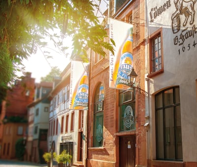 Fassade eines historischen Gebäudes mit Sonneneinstrahlung und Bierwerbung.