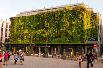 Gebäude mit grosser, grüner Pflanzenwand und Passanten.