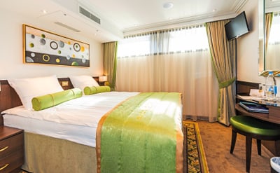 twerenbold_36817.jpg Helles Hotelzimmer mit grünem Dekor und Doppelbett.