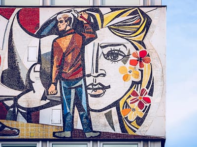 Bunte Wandkunst mit mannähnlicher Figur und Gesicht mit Blumen.