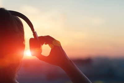 Person mit Kopfhörern vor Sonnenuntergang.