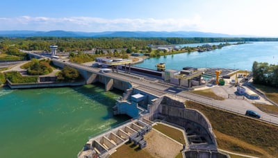 Luftaufnahme eines Staudamms mit Wasser, Strassen und angrenzender Landschaft.