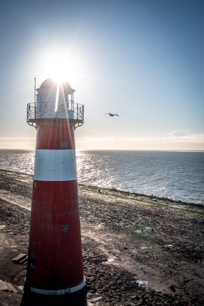 Roter Leuchtturm am Meer bei Sonnenschein.