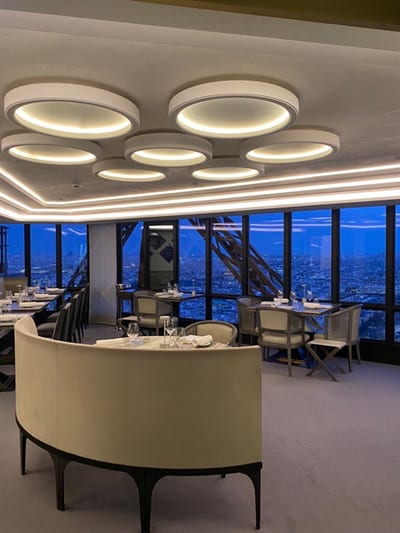 Elegantes Restaurant mit Blick auf die Stadt bei Abenddämmerung im Hintergrund.